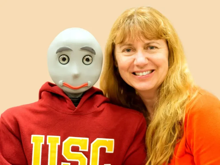 a smiling blonde woman poses with a humanoid robotic torso wearing a usc sweatshirt min 768x576