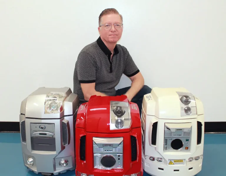 man crouches behind three robots min 768x600