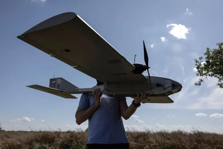 person holding a large drone outdoors under a sunny partly cloudy sky min 768x512