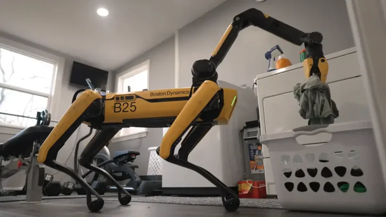 photo of yellow boston dynamics robot dog using its arm to load laundry into a white basket min 768x432