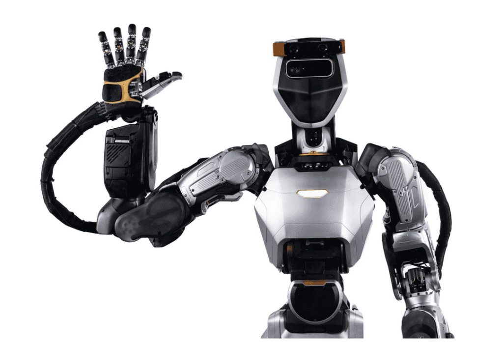 - RobotsInc.com Humanoid robot in silver and black raises its right hand in a friendly wave against a white background.