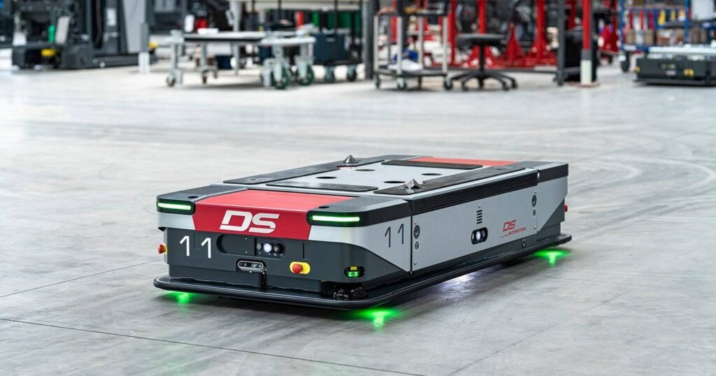 - RobotsInc.com Autonomous warehouse robot with a red DS panel, number 11, and green undercarriage lights on a concrete floor.