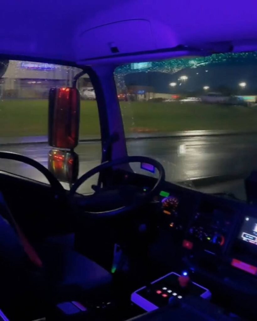 - RobotsInc.com Inside a vehicle cab at night with purple/blue ambient lighting and a visible dashboard.
