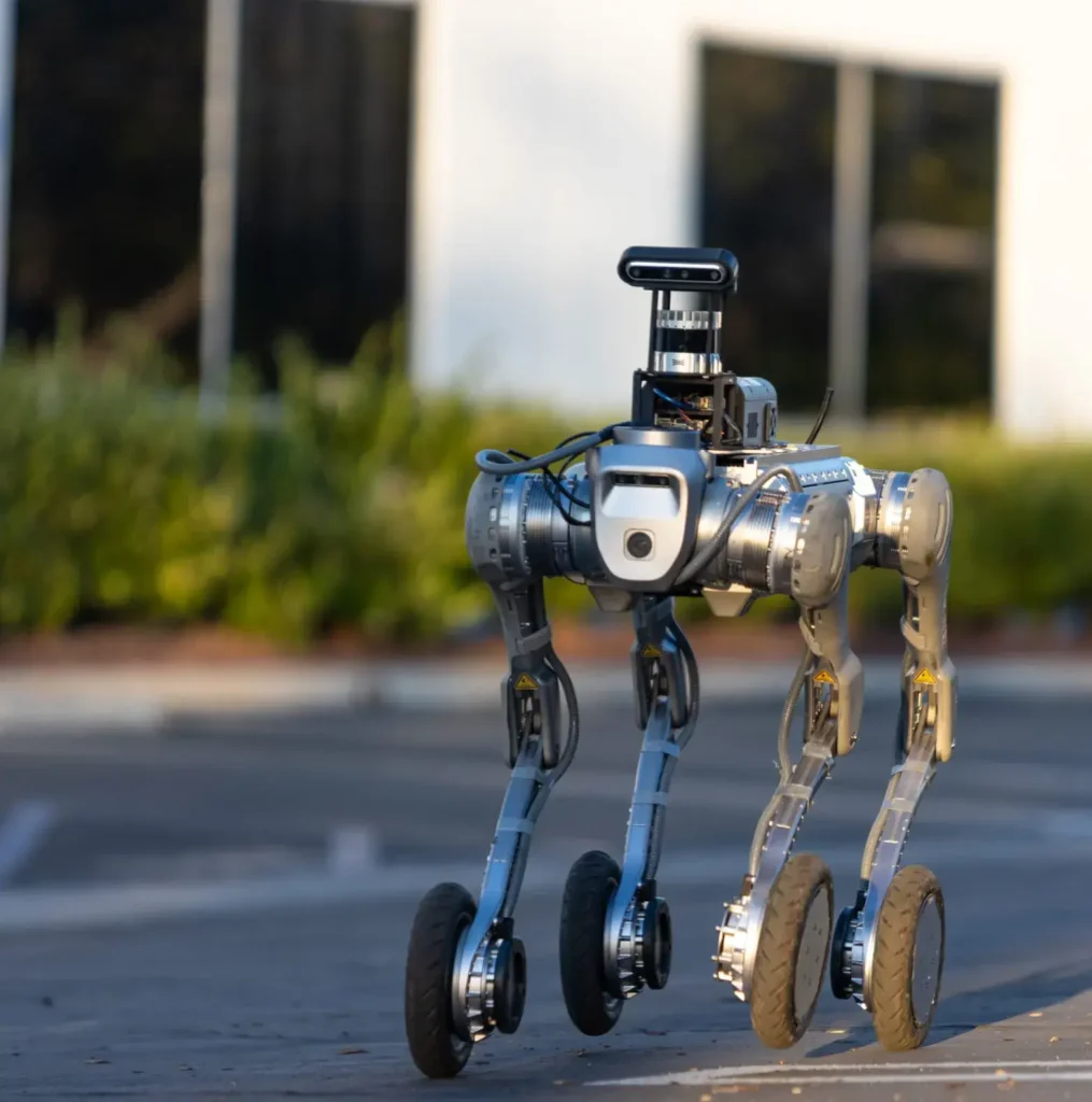 - RobotsInc.com Autonomous four-legged robot with wheeled feet standing on a street, camera/sensor module on top.