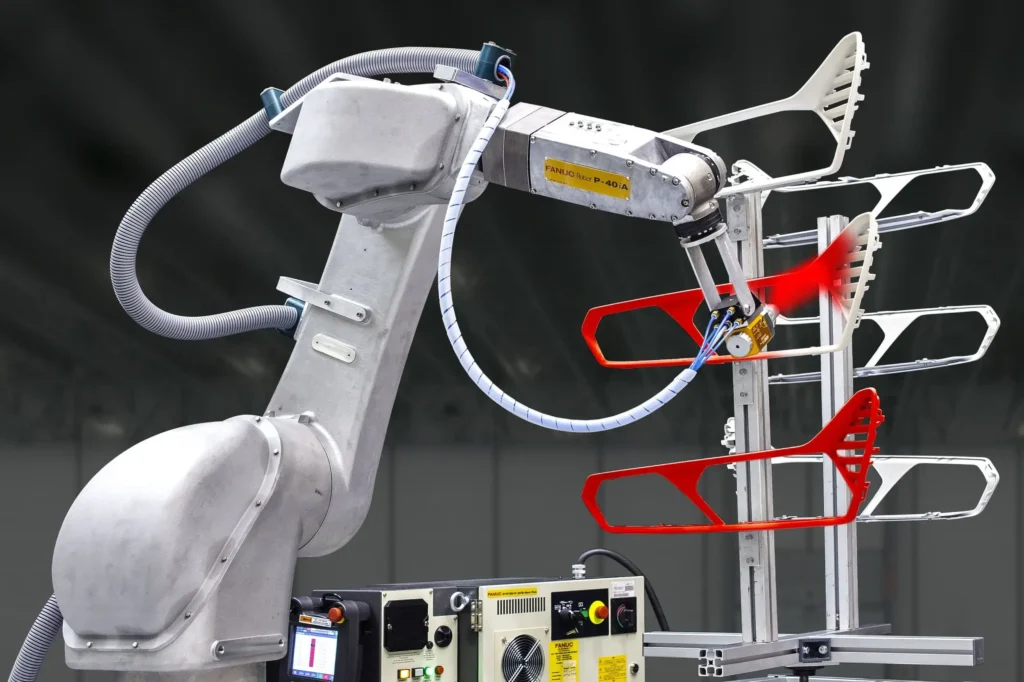 - RobotsInc.com FANUC industrial robotic arm with gray metal joints and attached control cabinet, set for automated manufacturing tasks.