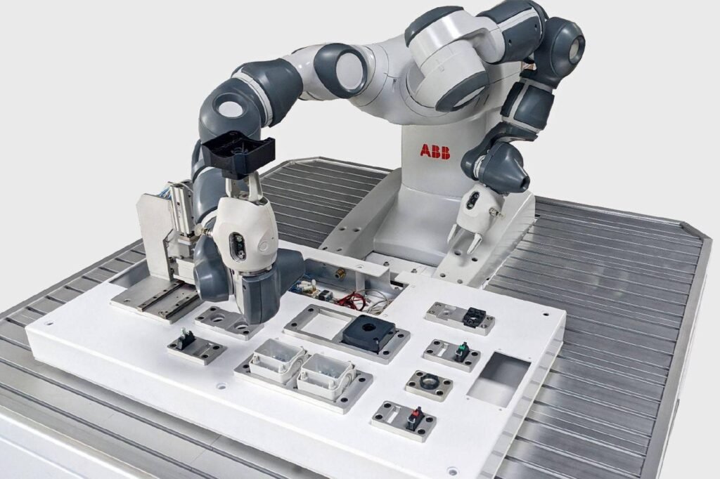- RobotsInc.com Industrial ABB robotic arm system performing automated manipulation on a white worktable with fixtures and wiring visible.