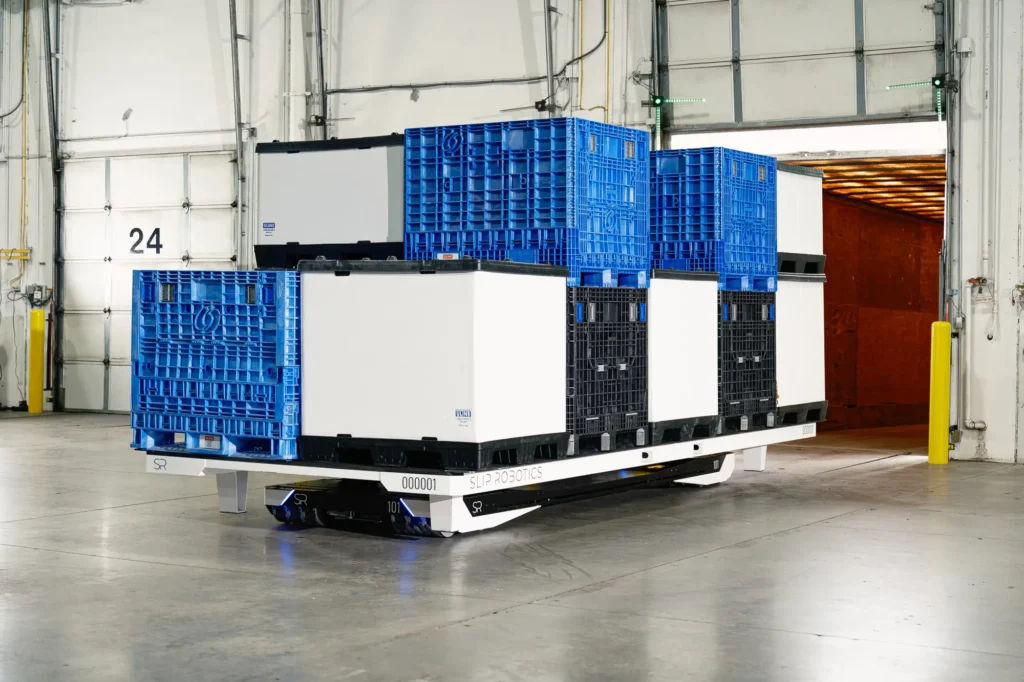 - RobotsInc.com Automated pallet robot carrying blue plastic crates in a warehouse loading area