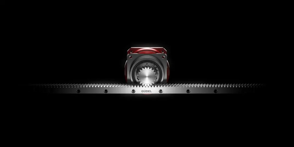 - RobotsInc.com Central metallic gear assembly with red housing above a long toothed rack against a black background.