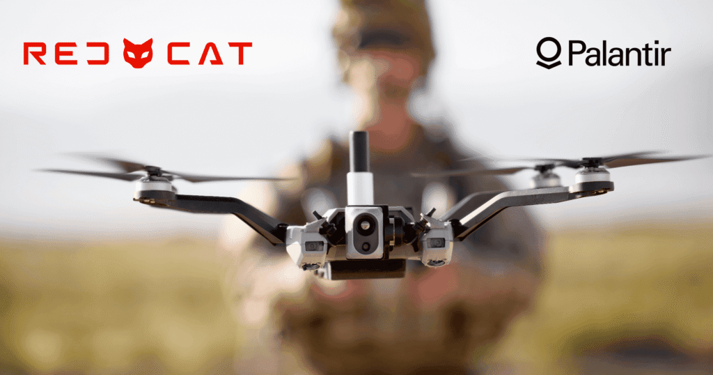 - RobotsInc.com Close-up drone facing the camera, with a blurred person in the background and Red Cat logo on the left and Palantir logo on the right.