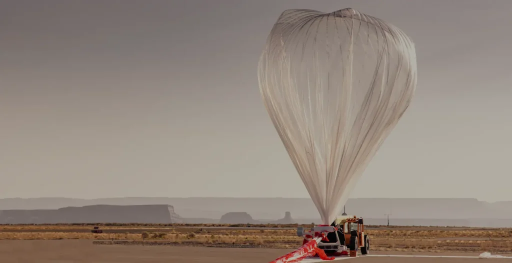 - RobotsInc.com White hot air balloon being inflated on a desert airstrip, with a support vehicle nearby and ground crew.