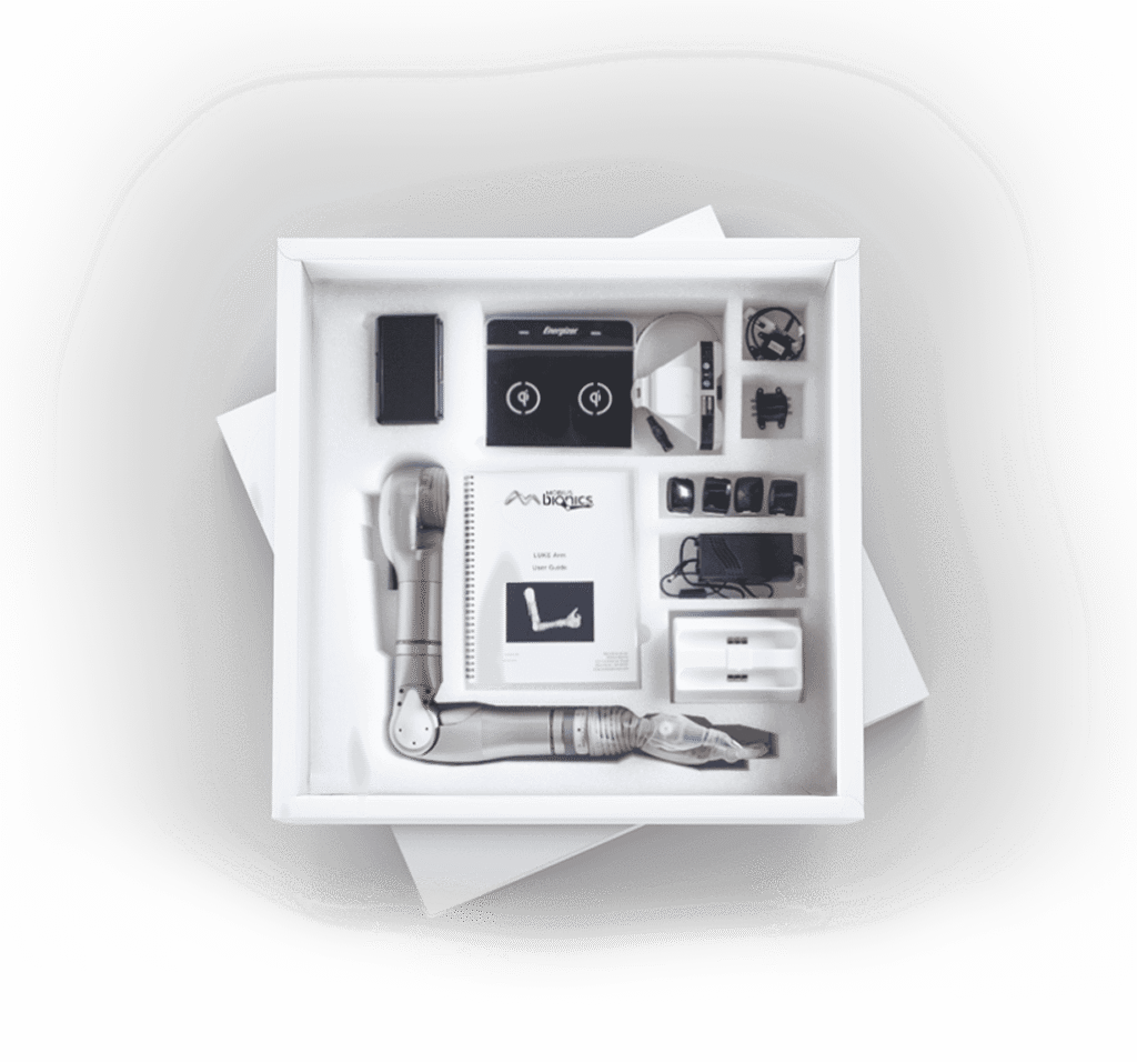 - RobotsInc.com Opened white box containing a prosthetic limb kit with modular components, instruction manual, and small parts arranged in compartments