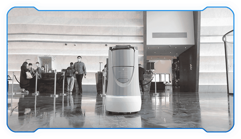 - RobotsInc.com Autonomous cleaning robot standing on a polished lobby floor with people at a reception area in the background
